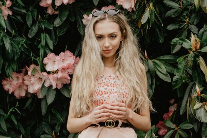Woman stands against flowers